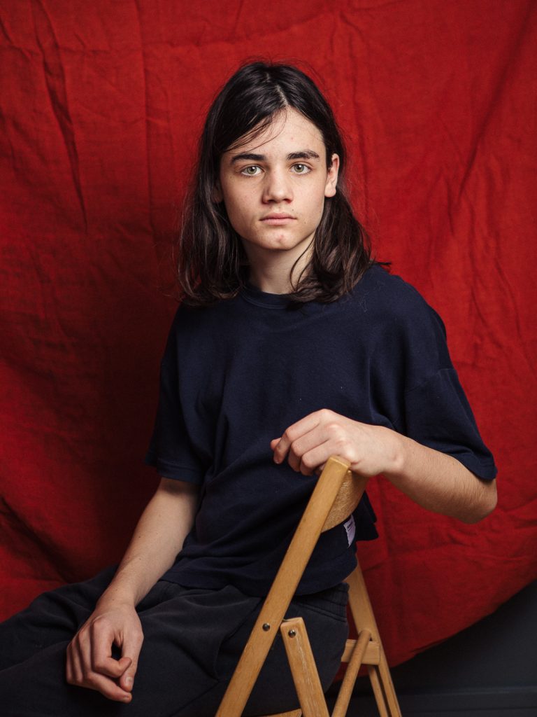 Portrait d'un adolescent en studio sur fond rouge.